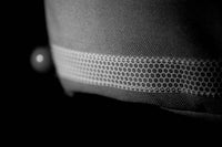Gilet Trisuli Aquadesign, détail bande réfléchissante hexagonale sur tissu gris, visibilité nocturne