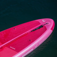 Arrière du SUP gonflable Orya 10' rose Aquadesign sur l'eau, leash rouge enroulé et ailerons visibles